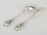 a pair of silverware with green stones on them