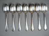 six silver spoons are lined up in a row on a table
