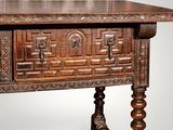 an old wooden table with a carved top and legs