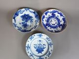 trois assiettes bleues et blanches à motifs posées sur une table