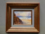 tableau à l'huile encadré représentant une scène de plage avec un voilier au loin