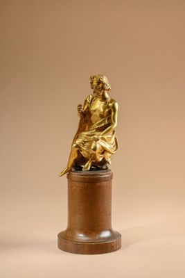 bronze statue of a woman sitting on a pedestal on a beige background