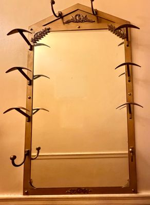 a mirror hanging on the wall above a shelf with hooks