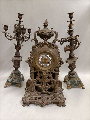a clock that is sitting on a table next to three candles