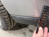 a person holding a measuring tape to measure a car ' s tire