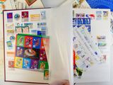 une personne tenant un livre ouvert sur lequel sont collés plusieurs timbres