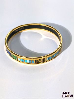un gros plan d'un bracelet en or orné de pierres bleues et vertes