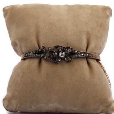 une photo d'un oreiller marron sur lequel est posé un bracelet noir et blanc