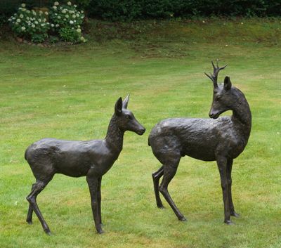 deux statues de cerfs dressées dans un champ herbeux