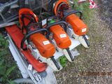 three chainsaws are sitting on top of a rack in the grass