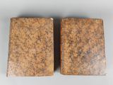 two old books sitting on top of each other on a table