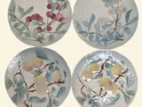 four plates with flowers and leaves painted on them on a white background