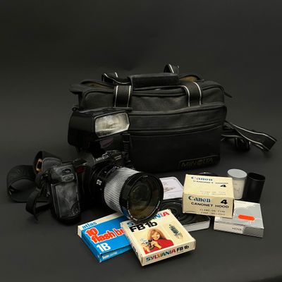 un sac noir contenant un appareil photo, un objectif et d'autres objets, posé sur une table