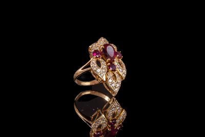 une bague en or sertie d'un rubis et de diamants sur un fond noir