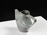 a silver vase sitting on a white surface