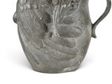 a gray vase with a bird on it on a white surface