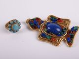 a close up of a broochle and a ring on a white surface