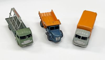trois camions miniatures posés les uns à côté des autres sur une surface blanche