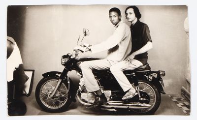 deux hommes assis sur une moto, posant pour une photo