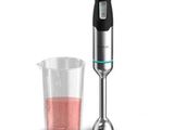 le mixeur se trouve à côté d'un verre contenant un liquide