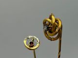 a gold flower with a red stone in the middle