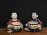 two figurines of asian men sitting on a table