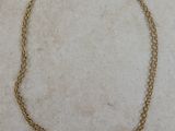 un gros plan d'un collier à chaîne en or posé sur une surface en marbre