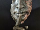 statue of a man with a finger on his lips holding a piece of paper