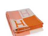 an orange and white blanket with the letter h on it
