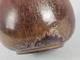 a brown vase that is sitting on a white table