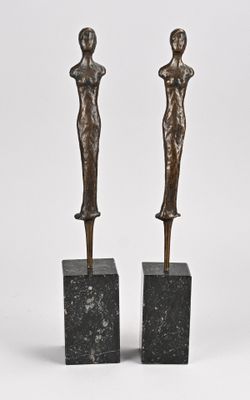 une paire de sculptures en bronze représentant une femme et un homme, posées sur des socles en marbre