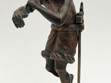 une vieille statue en bronze représentant un homme muni d'une canne