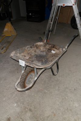 une brouette au milieu d'un garage, avec une échelle à côté