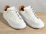 the white sneakers are on a wooden table with a white background