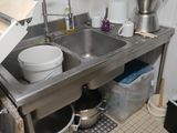 un évier en acier inoxydable dans une cuisine où des casseroles et des poêles sont posées sur le plan de travail