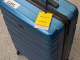 une valise bleue avec une étiquette, posée par terre