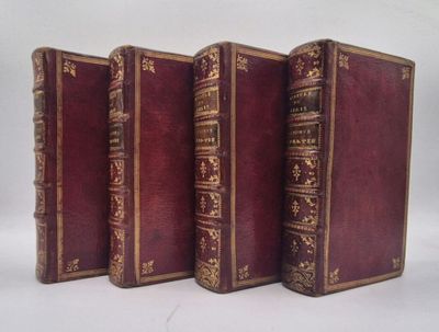 trois vieux livres sont alignés sur une surface blanche