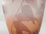 a purple vase with leaves on it sitting on a table
