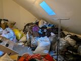 a pile of clothes and bags in a room with a skylight