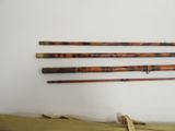 three old fishing rods are lined up against a white wall