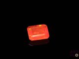 a close up of an orange diamond on a black surface