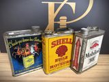 three vintage shell oil cans sitting on top of a wooden table