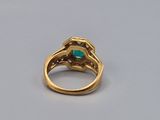 a close up of a gold ring with a green stone in it