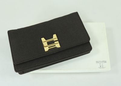 un sac à main noir orné d'une boucle dorée sur le dessus