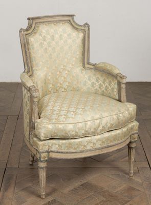 une vieille chaise dont l'assise est recouverte d'un tissu à motifs, posée sur un parquet