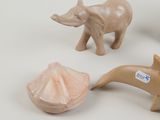 three figurines of elephants and a shell on a white surface