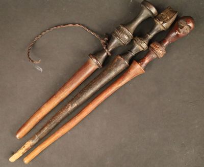paire de cannes anciennes en bois avec des poignées en métal sur un fond gris