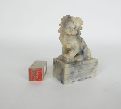 statue of a dog sitting on a box next to a small box with a chinese writing on it