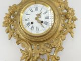 une horloge en or accrochée au mur à côté d'une feuille de papier