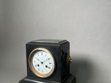 a small black clock sitting on top of a table